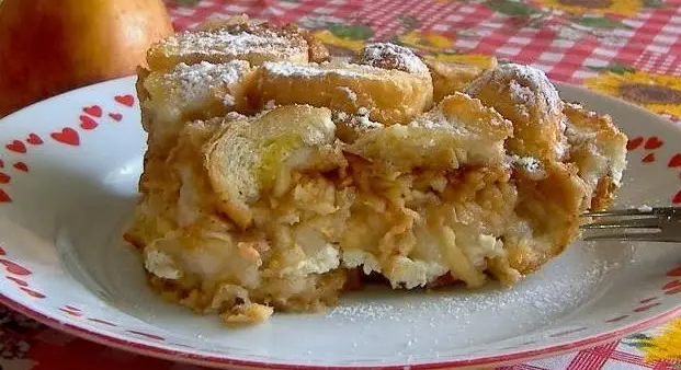 Kousek jablkového štrúdlu posypaný cukrem na talíři.