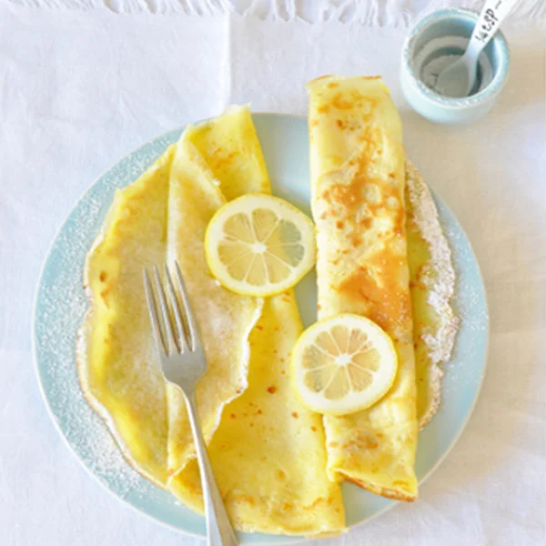 Zlaté palačinky s citronovými kousky na talíři.