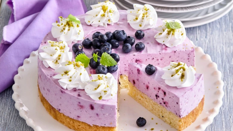 Sýrový dort s borůvkami a mascarpone na bílém talíři.