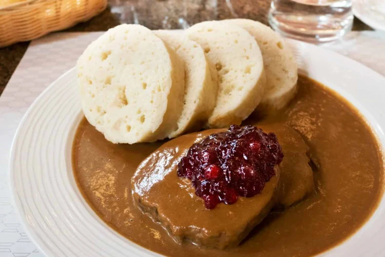 Svíčková s knedlíkem a brusinkovou omáčkou na talíři.