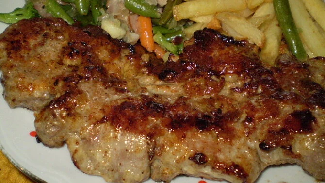Připravená krkovice na pánvi s bramborami a zeleninou.
