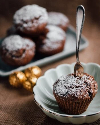 Čokoládové muffiny posypané cukrem na talíři.