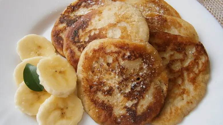 Pancake s přezrálými banány na bílém talíři.