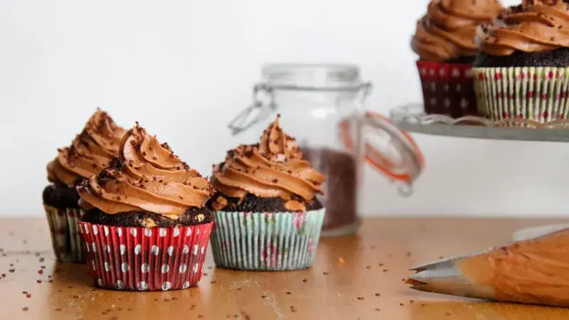 Tři čokoládové muffiny s mrazenou náplní na dřevěném stole.