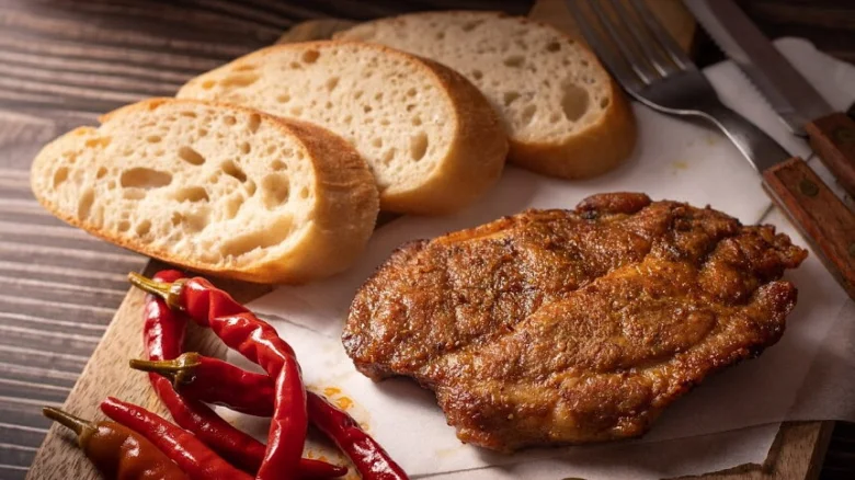 Připravené vepřové kotlety s chlebem a červenými chilli papričkami.