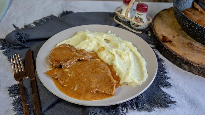 Pork with mashed potatoes and brown sauce.