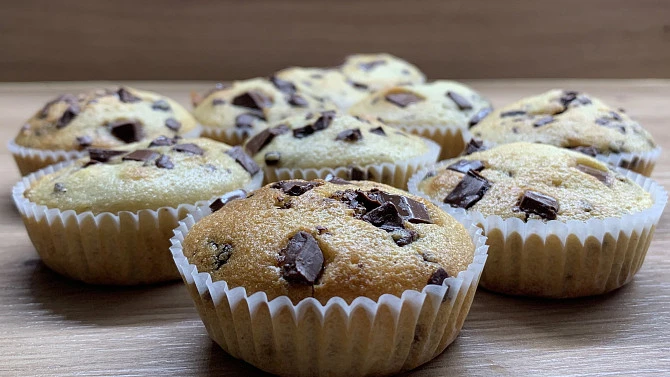 Zlatohnědé muffiny s čokoládovými kousky v papírových formách.
