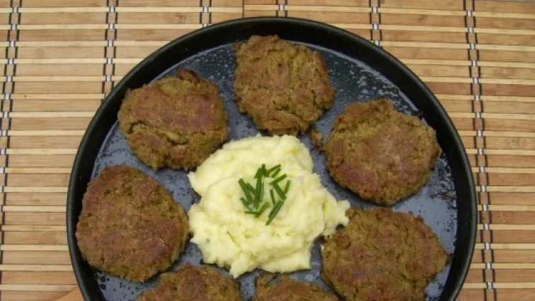Připravené masové karbanátky s bramborovou kaší na talíři.