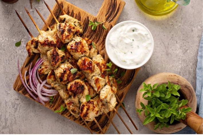Grilované kuřecí špeky souvlak s cibulovými kroužky a česnekovou omáčkou.