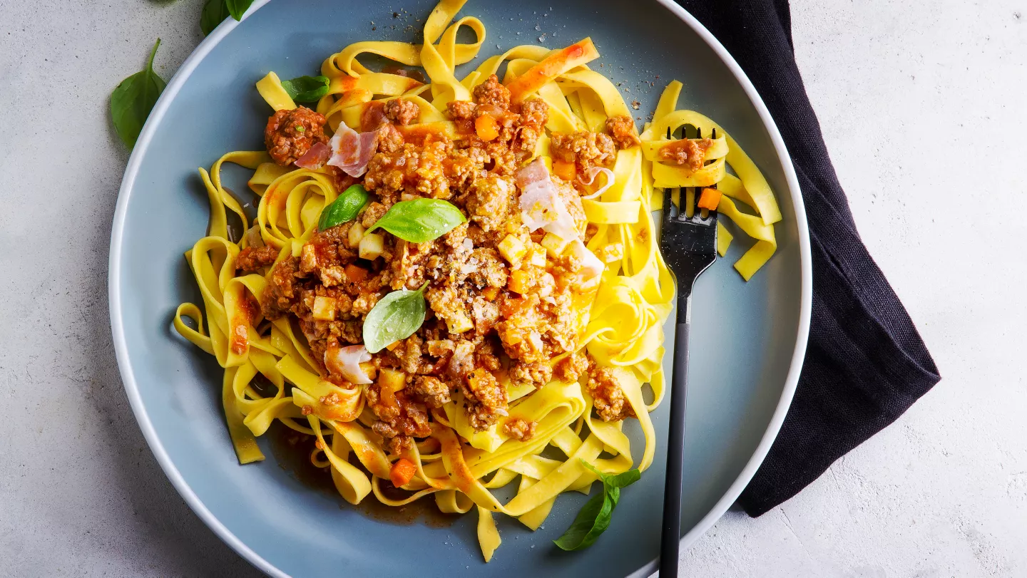 Pasta s boloňskou omáčkou na modlém talíři.