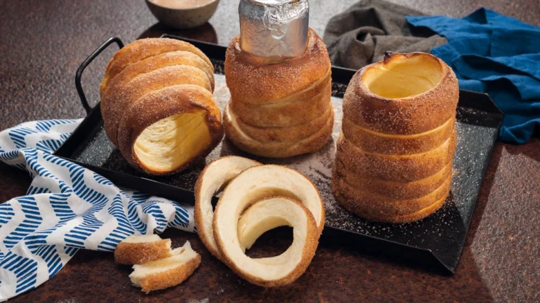 Trdelník posypaný cukrem s viditelnou vnitřní strukturou.