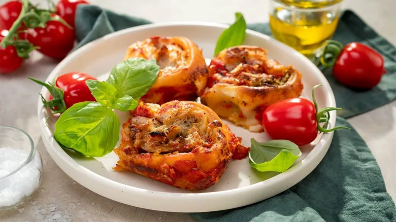 Pecené pizzové šneky s bazalkou a rajčaty na talíři