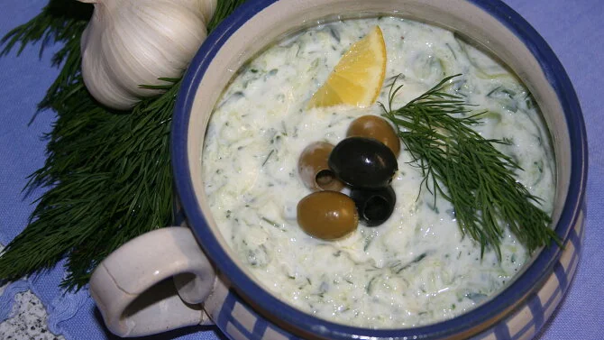 Miska s domácí tzatzikem ozdobená olivami, citronem a koprem.