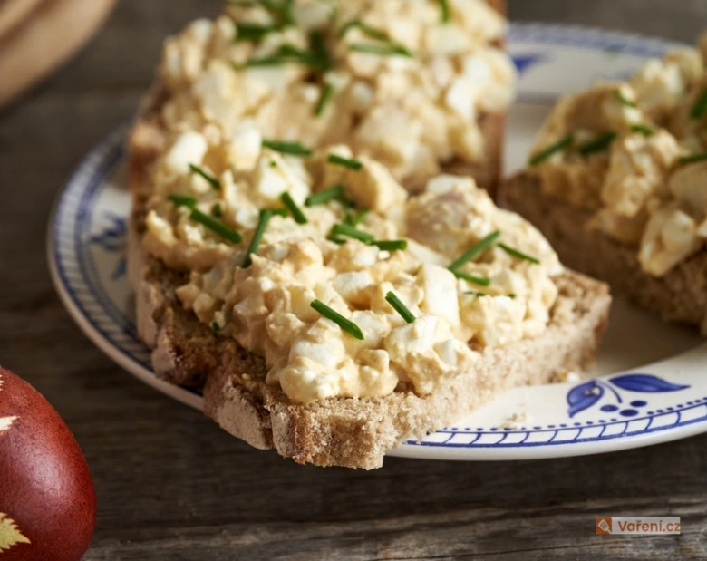 Kousek celozrnného toastu s vejcovou pomazánkou bez majonézy a cibulkami.