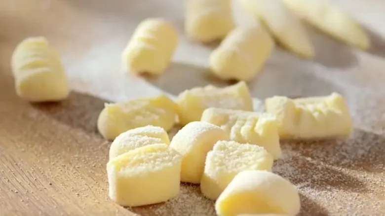 Svěžá knoche na dřevěném povrchu posypané moukou.