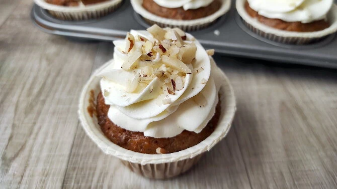Mrkvový cupcake s bílým krémem a nasekanými ořechy.