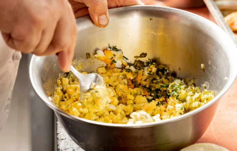 Míchání ingrediencí pro vajíčkovou pomazánku ve stříbrné misce.