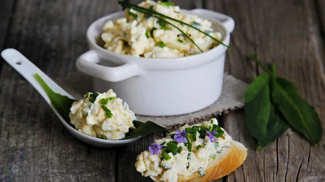 Vajíčková pomazánka s cottage na toastu v bílé misce.