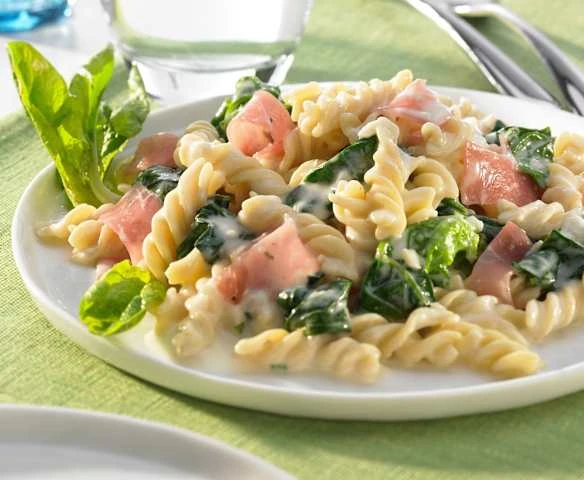 Pasta s špenátem v omáčce na talíři.
