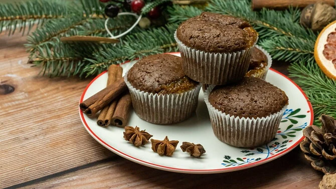 Perníkové muffiny s kořením na talíři mezi borovicovými větvemi.