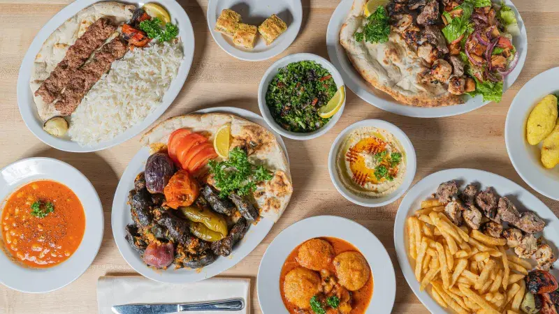 Turecká jídla: kebab, rýže, houmous a zelenina na stolu.