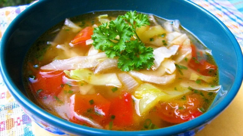 Hot vegetable soup in a blue bowl ready to eat.