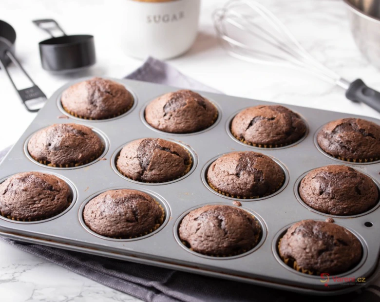 Čerstvě upečené čokoládové muffiny v plechu na mramorovém povrchu