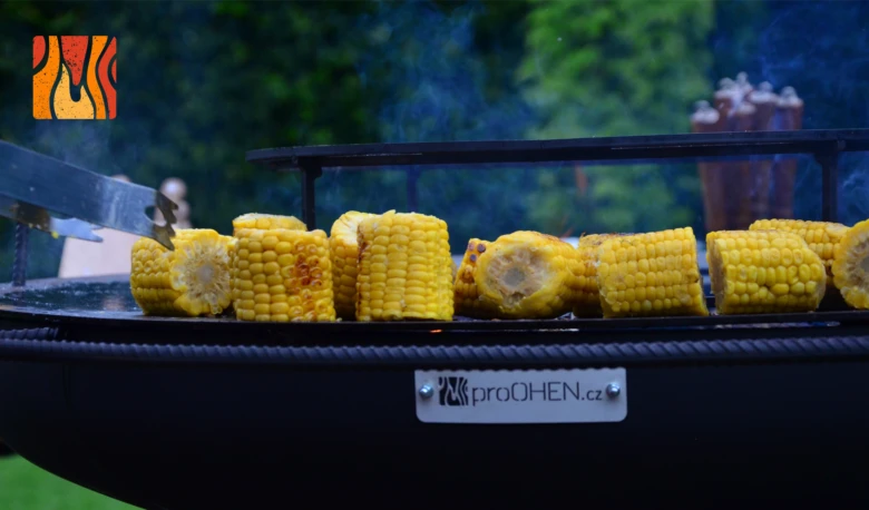 Grilovaná kukuřice na grilu s dýmem v pozadí