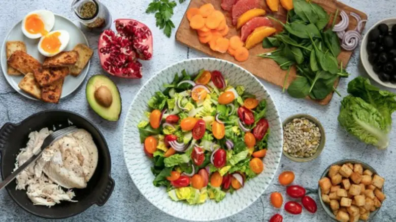 Suroviny na salát: rajčata, listová zelenina, avokádo a ostatní ingredience.
