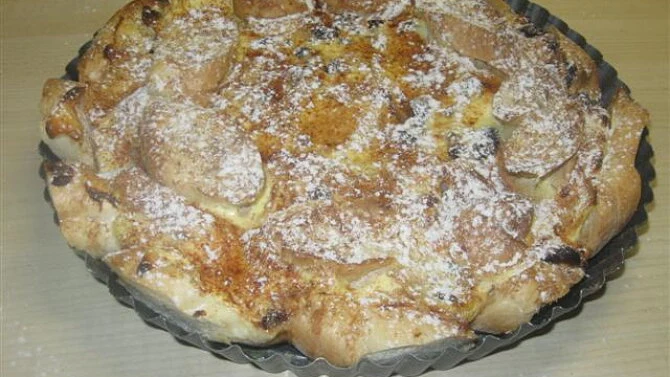 Zapečená žemlovka posypaná moučkovým cukrem v pekáči.