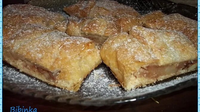 Zlatohnědé štrúdlíky posypané moučkovým cukrem na talíři.