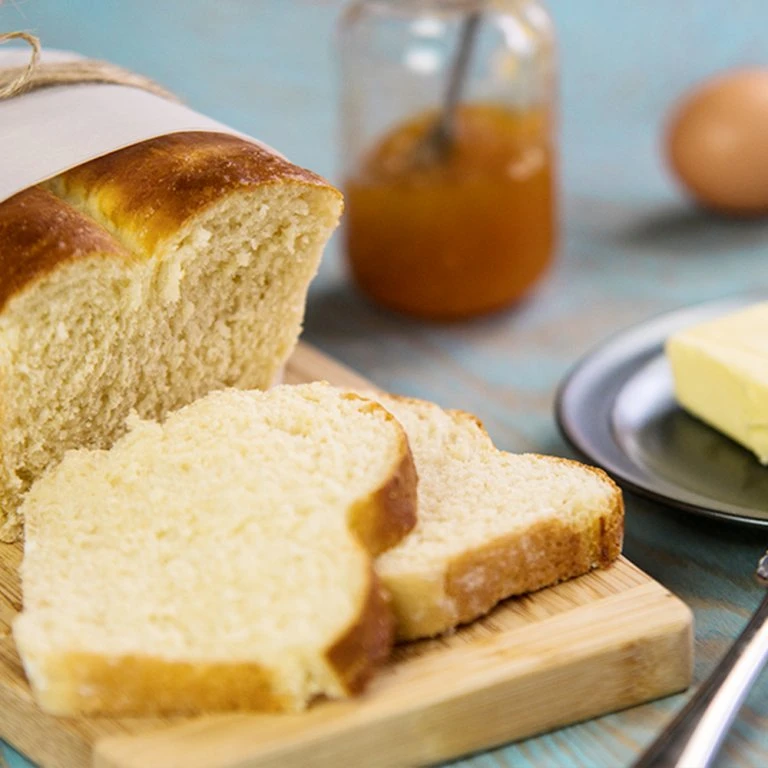 Domácí chléb nakrájený na plátky s máslem a marmeládou.