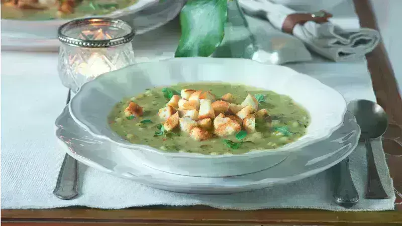 Miska hrachové polévky s chlebíčky a bylinkami.