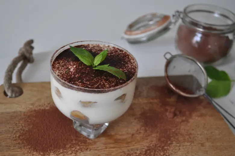Hotový tiramisu v skleněné misce s čokoládou a mátou.