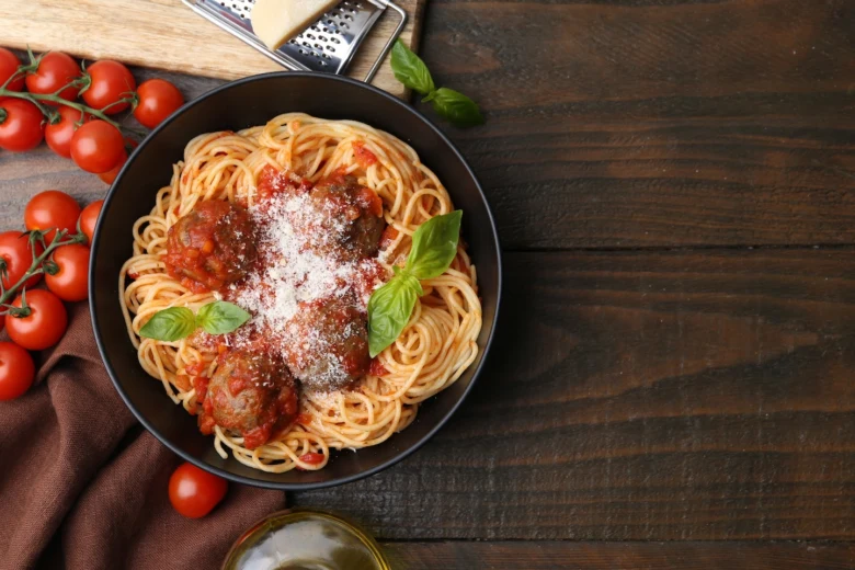 Spaghetti s masovými kuličkami v rajské omáčce posypané parmezánem.