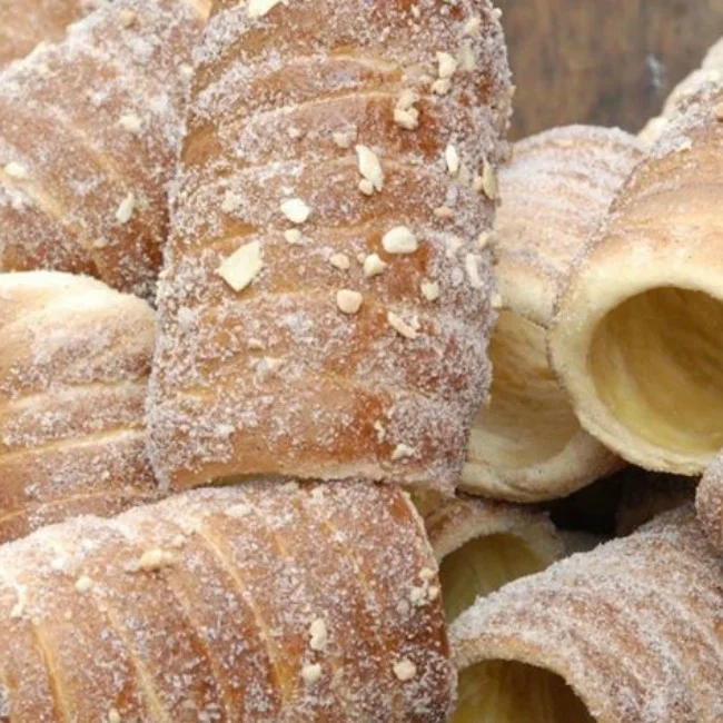 Trdelníky posypané cukrem a ořechy, hotové sušenky.
