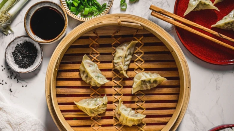Pět gyoza knedlíčků v bambusovém páře s omáčkou.