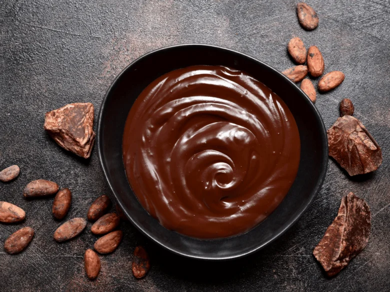 Čokoládová ganache v černé misce s kousky kakaa.