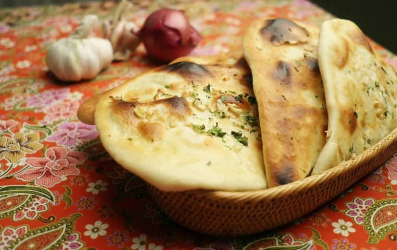 Kos s indickým chlebem naan posypaným bylinkami.