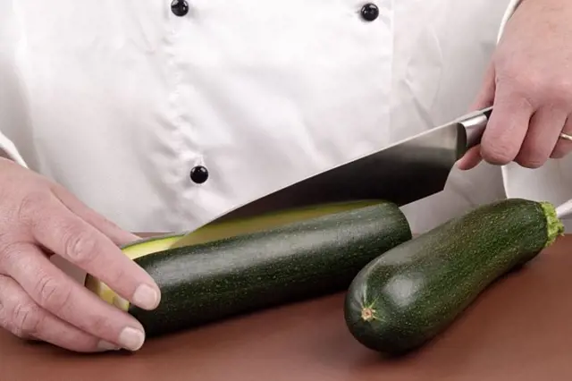Šéfkuchař krájí cuketu na recept s těstovinami.