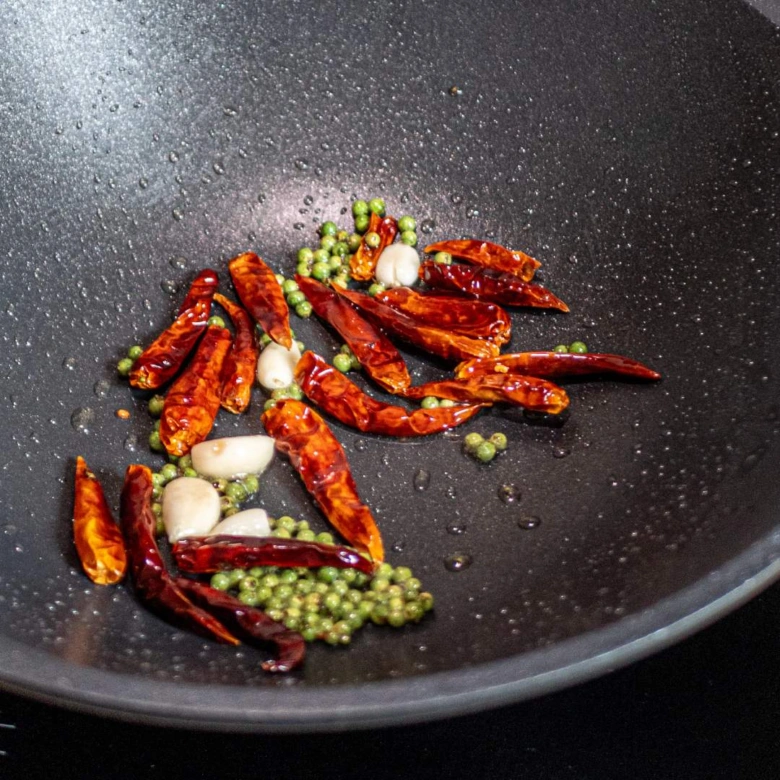 Smažené chilli, česnek a zelené pepře v pánvi pro kuřecí recept.