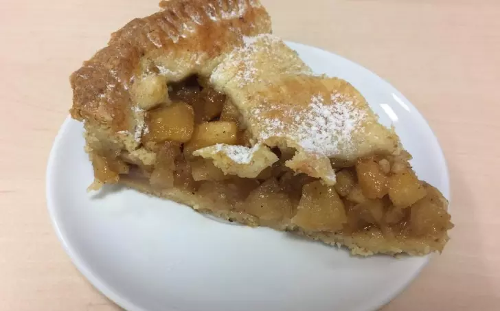 Kousek lineckého koláče s jablky na bílé talíři.