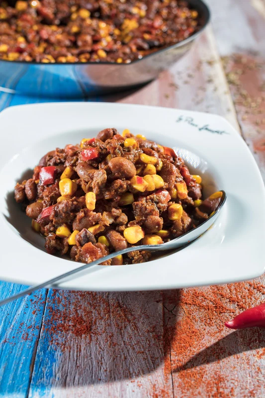 Hotová chilli s fazolemi a kukuricí v bílé misce.