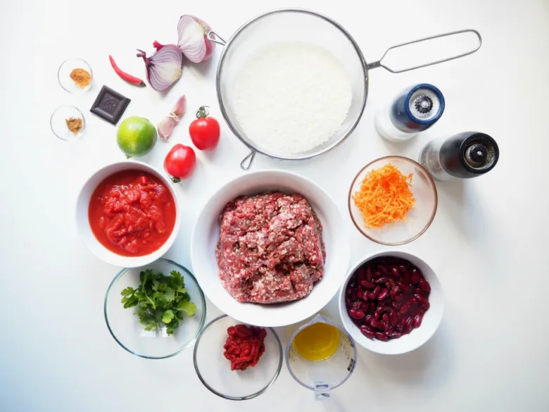 Suroviny pro chili con carne: mleté maso, rajčata, cibule, papriky a další.