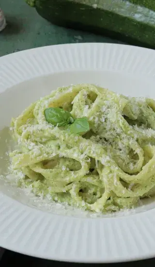 Pasta s cuketovou omáčkou posypaná syrem a bazalkou.