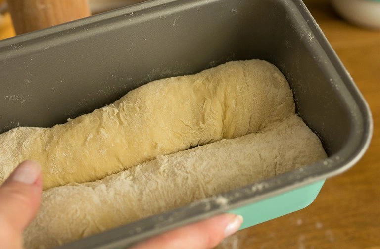 Kvasící těsto v pekáči připravené na domácí toustový chléb.