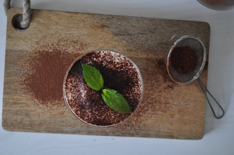 Hotový dezert Tiramisu s čokoládou na dřevěné desce.