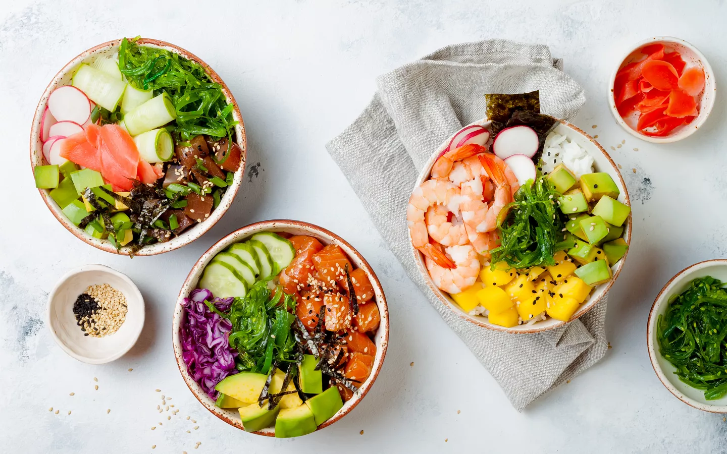 Tři barevné poke bowl s mořskými plody, zeleninou, avokádem a mango.
