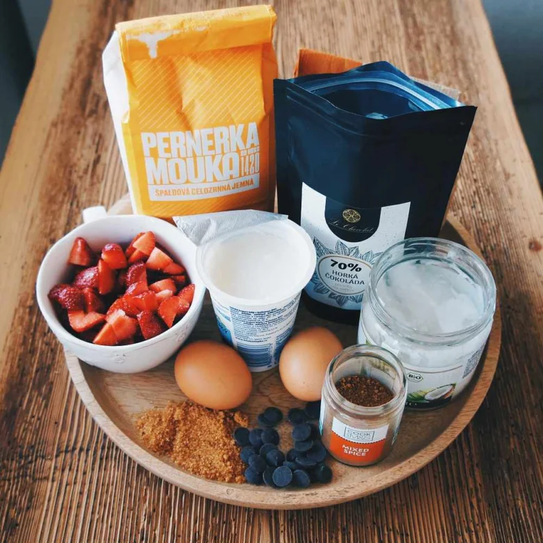 Ingredience pro jahodovou buchtu na dřevěném podnosu.
