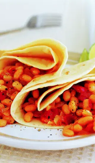 Mexické tacos s fazolemi na bílém talíři.
